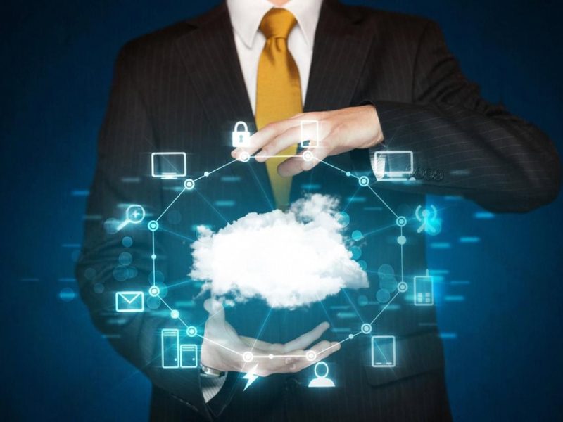 Businessman holding a cloud icon surrounded by connected IT service symbols representing cloud infrastructure in the UAE