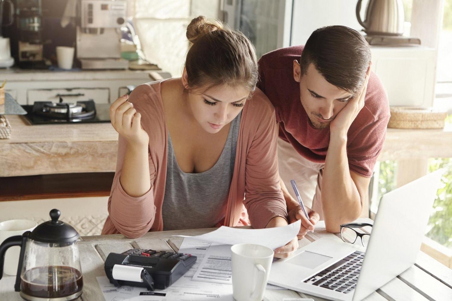 Couple in a UAE kitchen reviewing bills and using a calculator to plan their budget