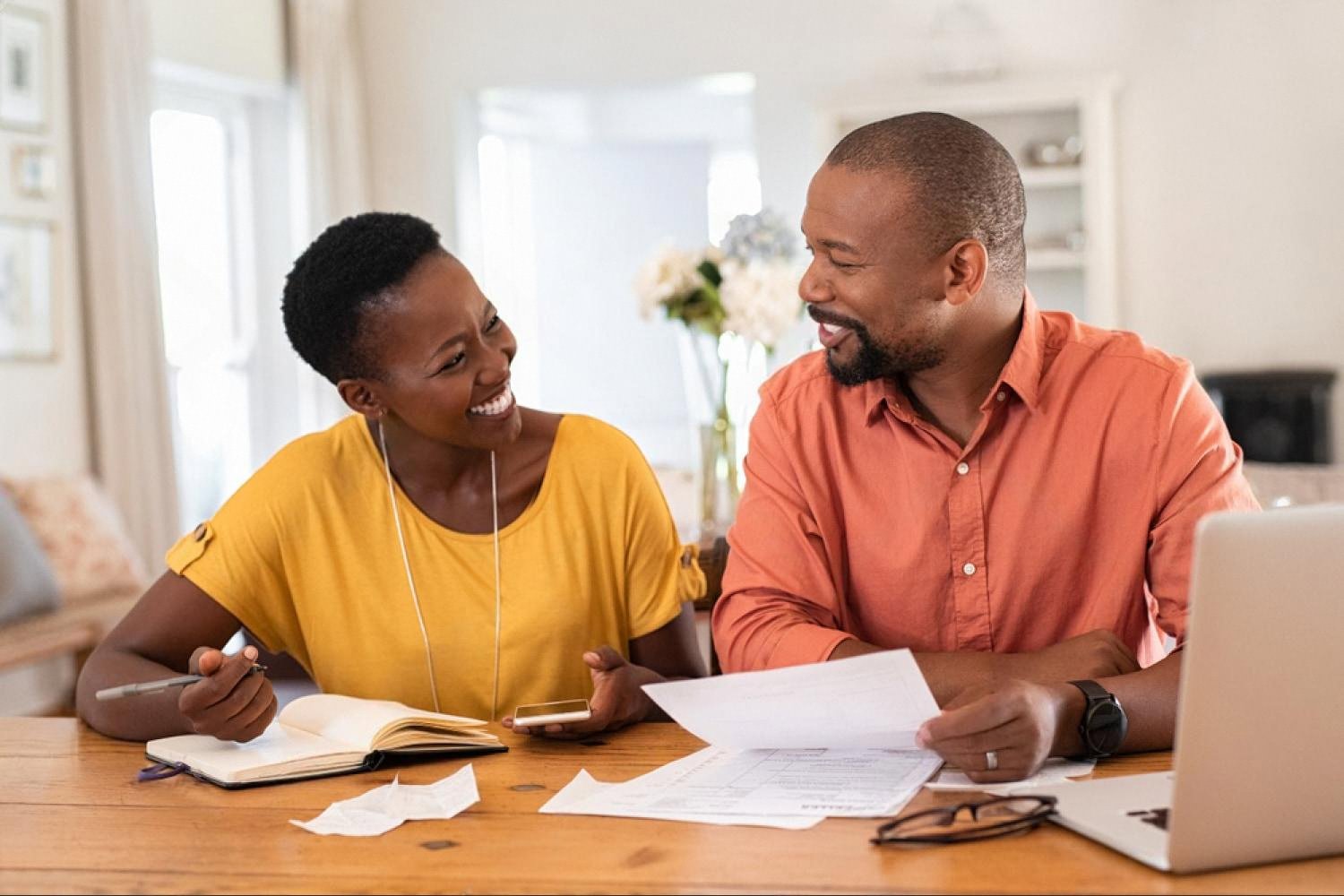 Young couple in the UAE smiling while reviewing personal finances at home